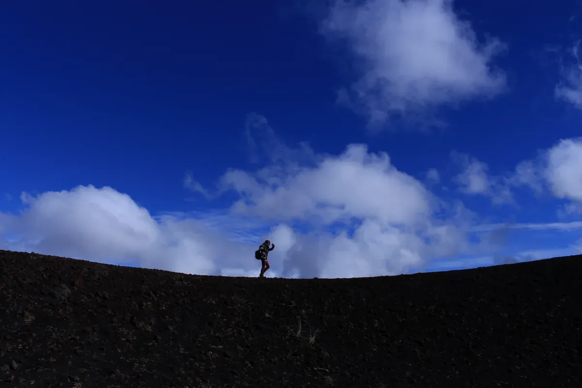 A hiker on the ridge of one of the Monti Sartorius craters on the north slope, seen on Mount Etna tours from Taormina, Sicily