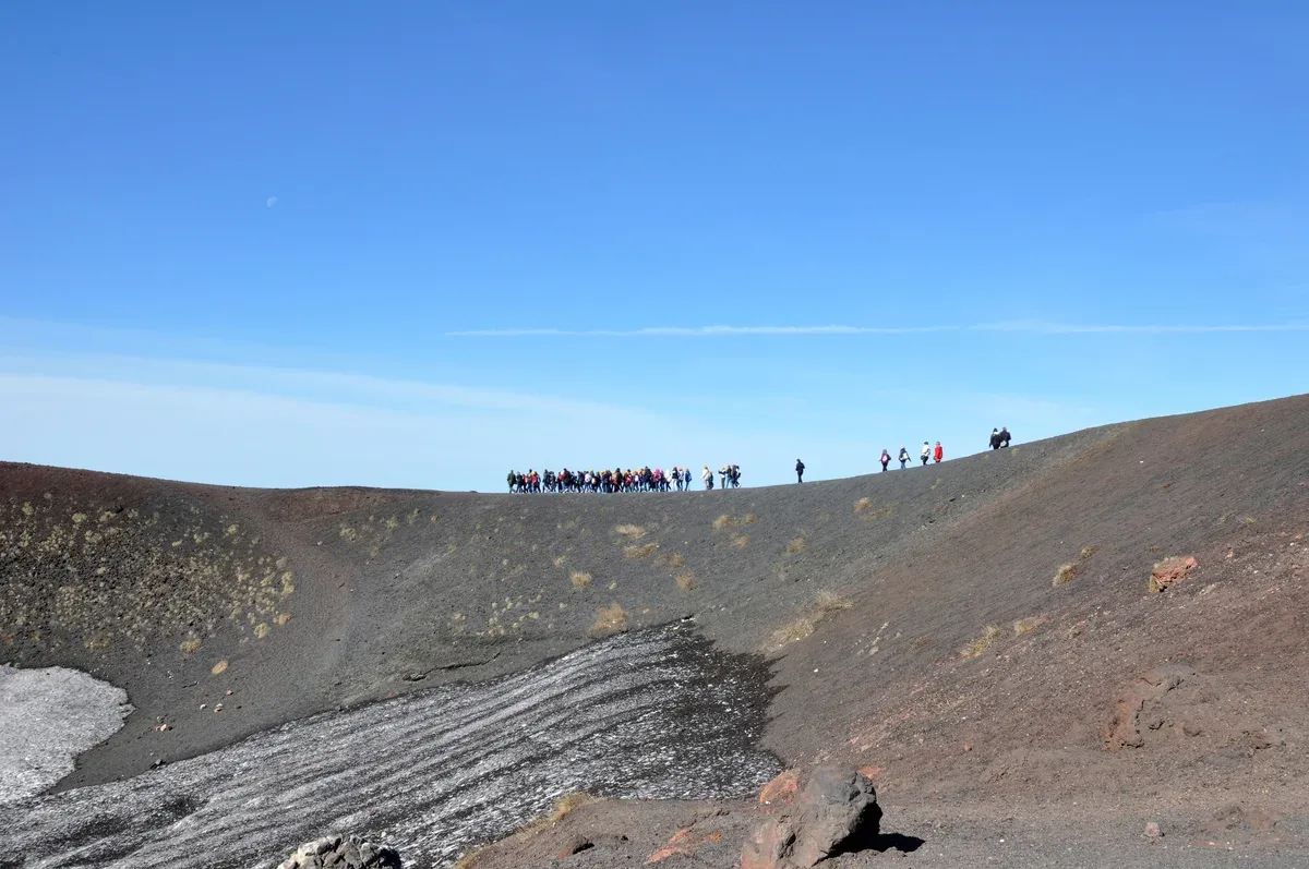 Walkers on the rim path of the Silvestri Craters, a stop on Mount Etna tours from Taormina, Sicily